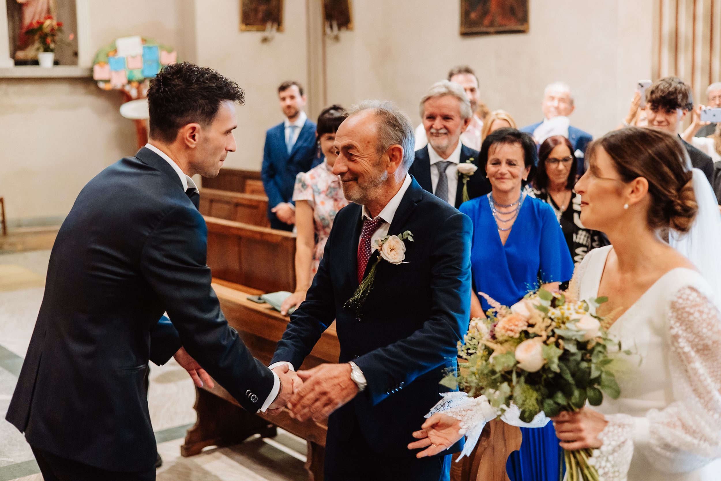 A joyful moment during a church wedding ceremony as people greet each other in the front pew.
