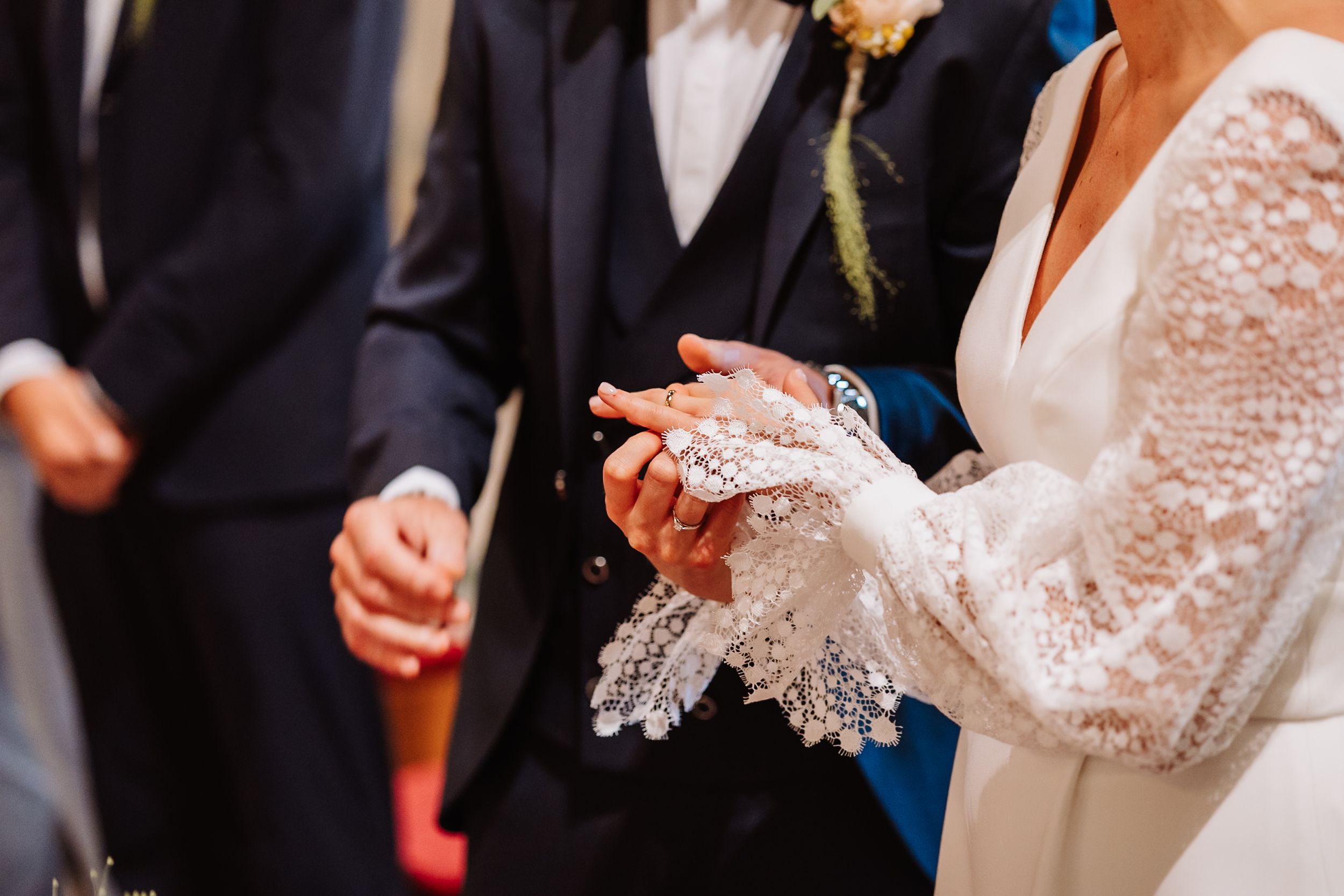 A couple in formal wedding attire holds hands during their wedding ceremony in a church.
