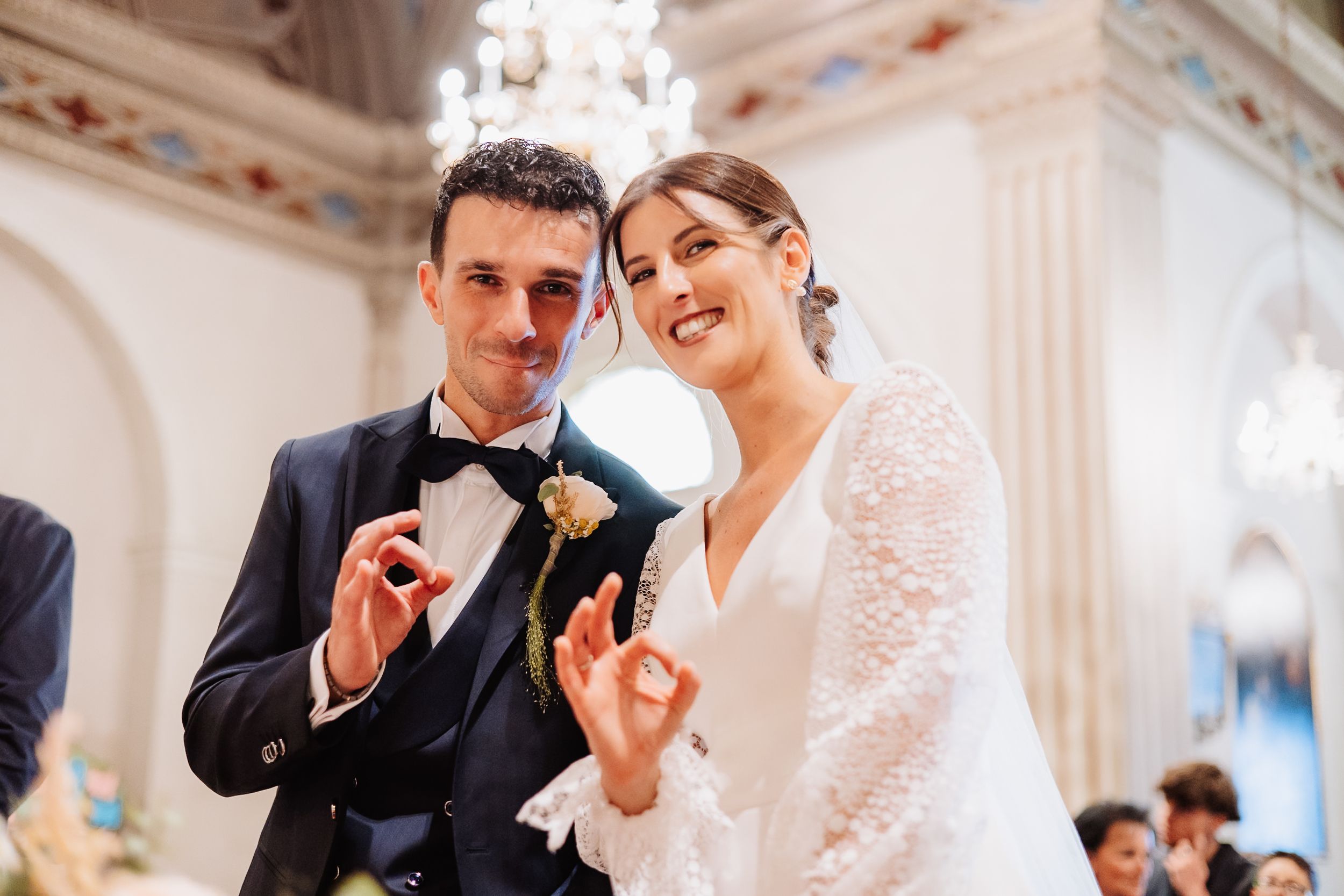 A happy couple shares joyful moments during their wedding celebration in an elegant white venue.
