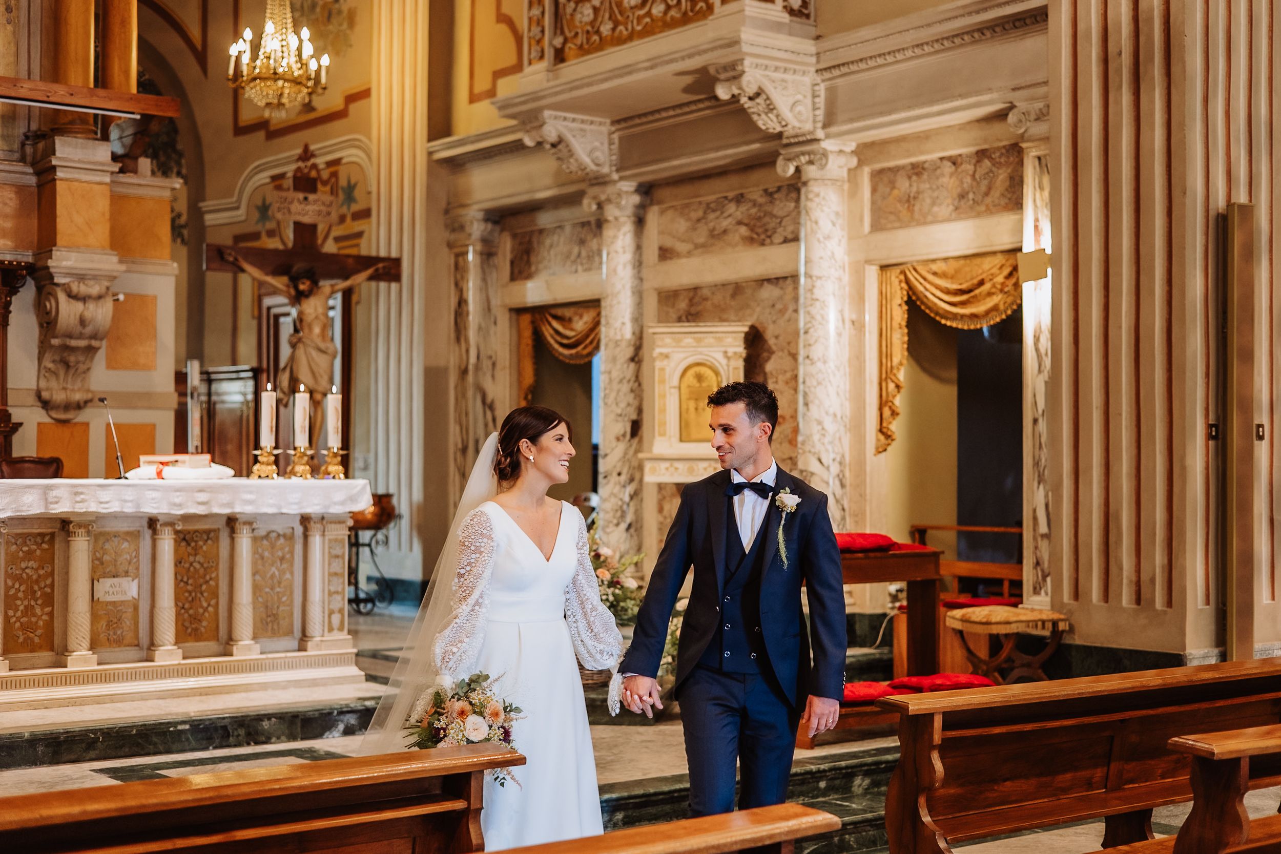 A panoramic view of an elegant church interior with marble columns and ornate architectural details during a ceremony.