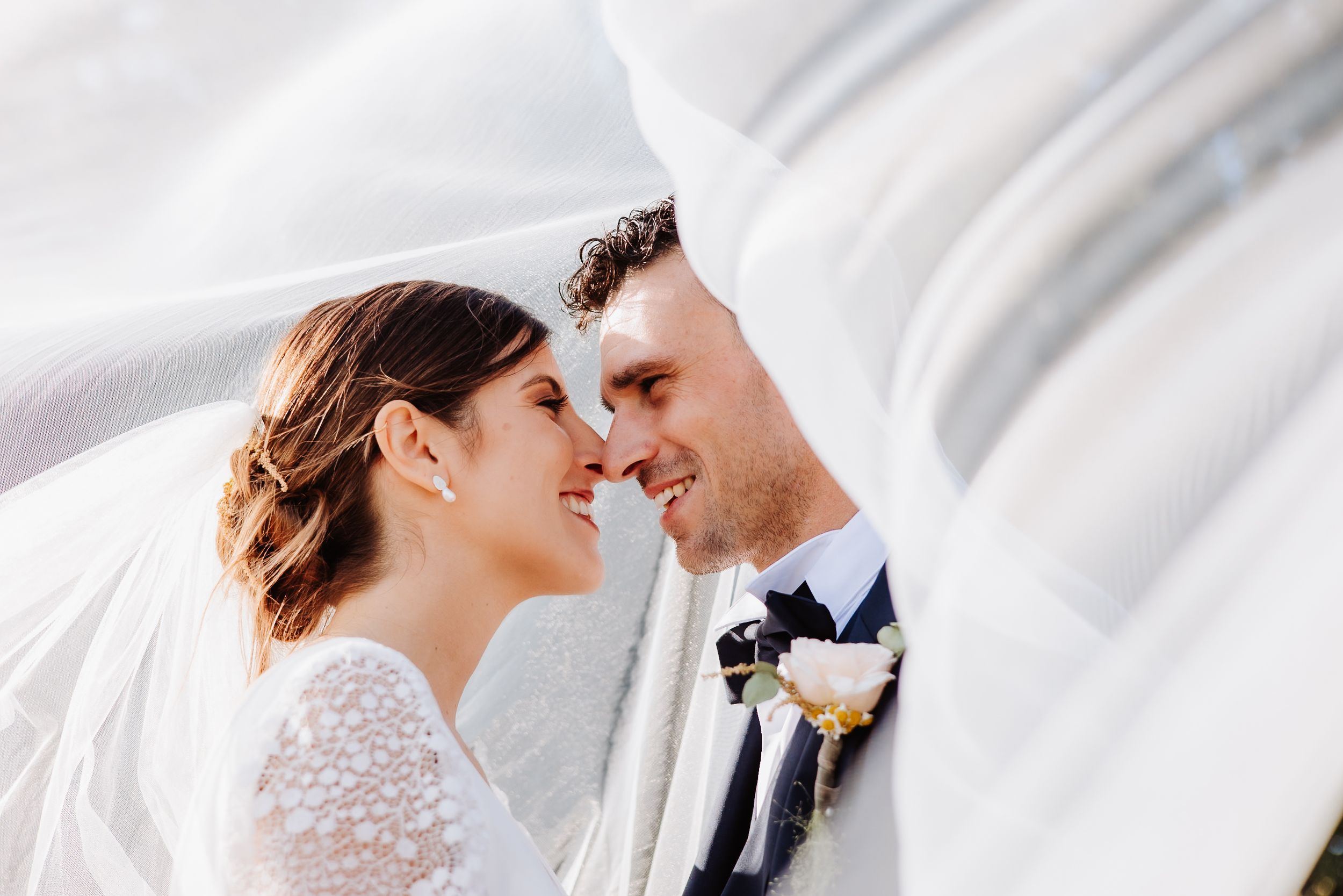 Romantic wedding couple shares intimate moments against a white backdrop in elegant formal attire.