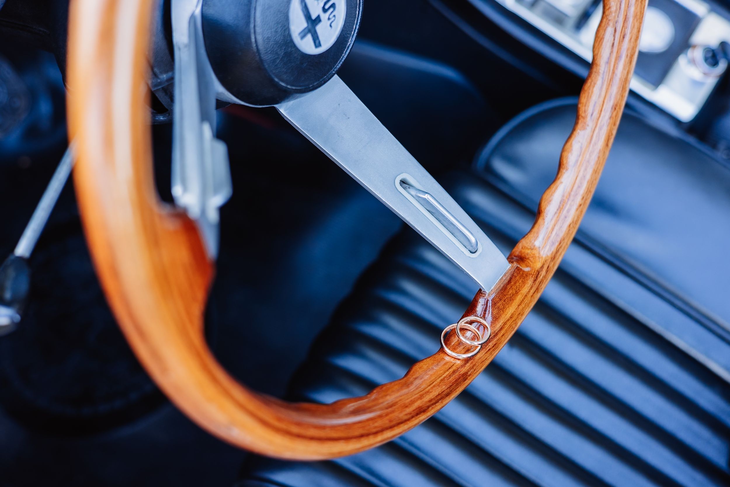 Close-up view of a brown leather steering wheel with blue dashboard visible in the background.