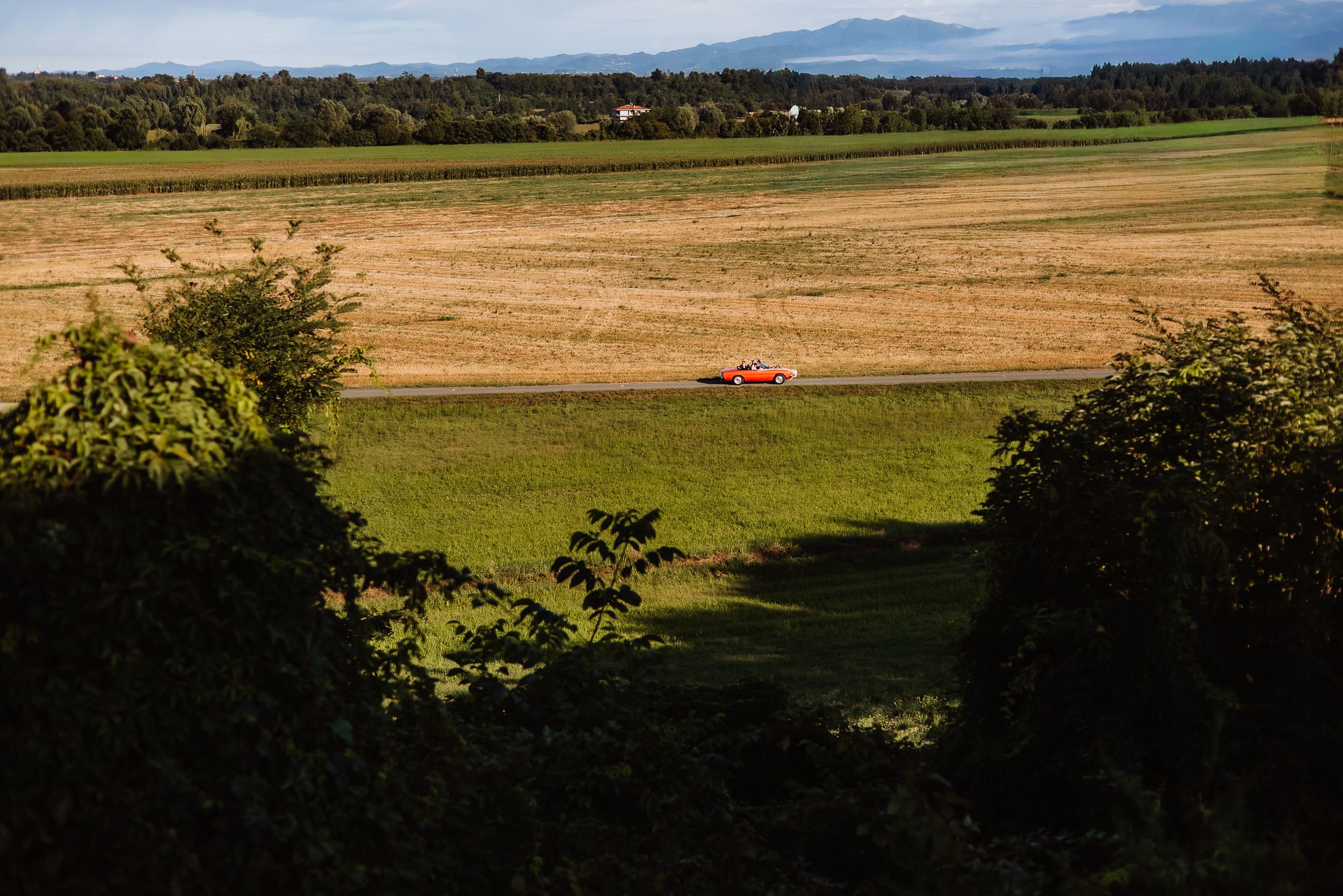 Scenic panoramic view of rolling farmland and mountains in the distance under a blue sky with scattered clouds.