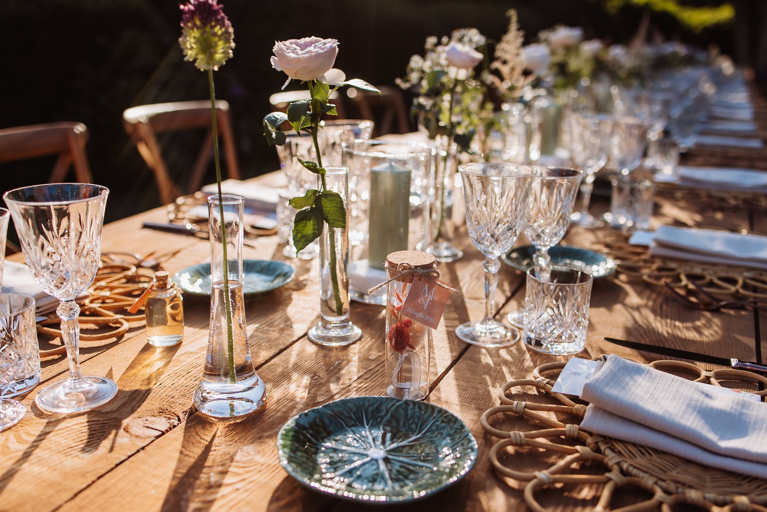 Elegant table setting with crystal glasses, delicate floral centerpieces, and place settings on a wooden table.