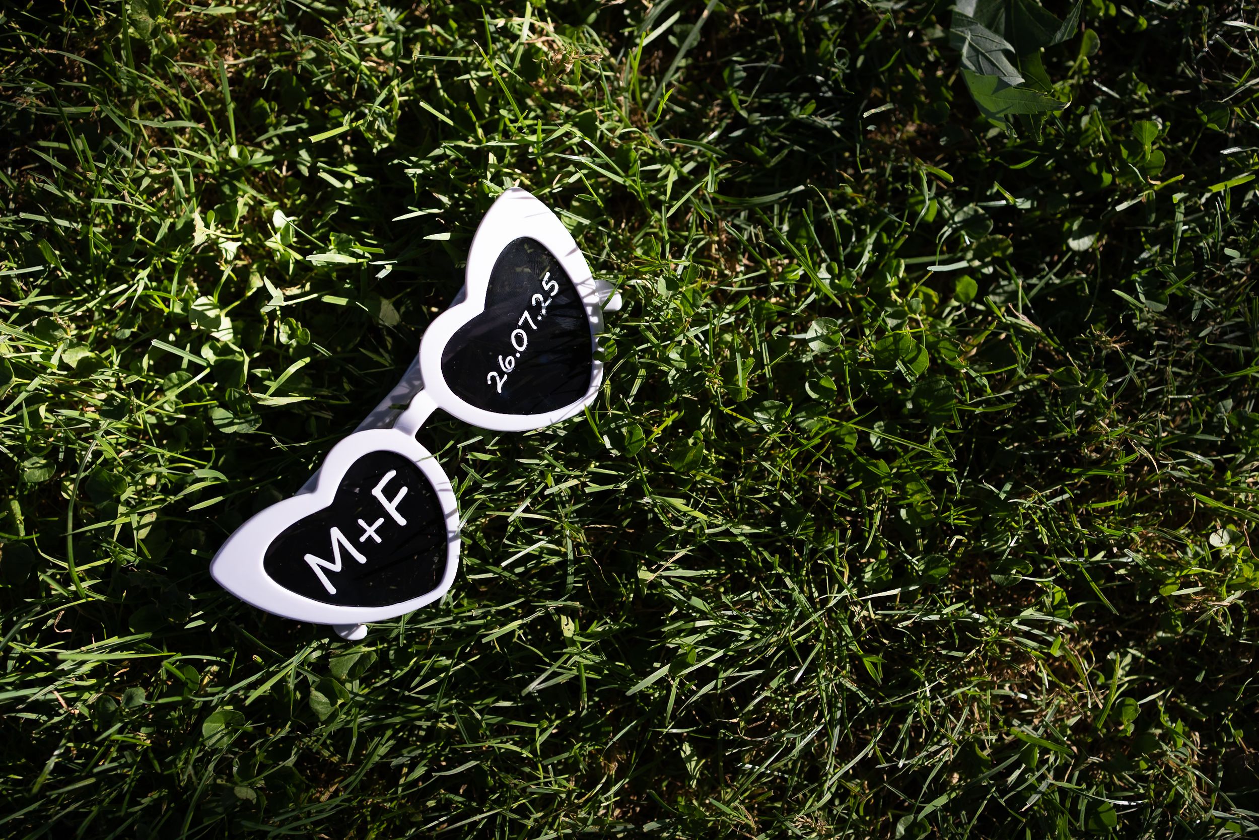 Black and white wedding shoes arranged on green grass in an artistic pattern.