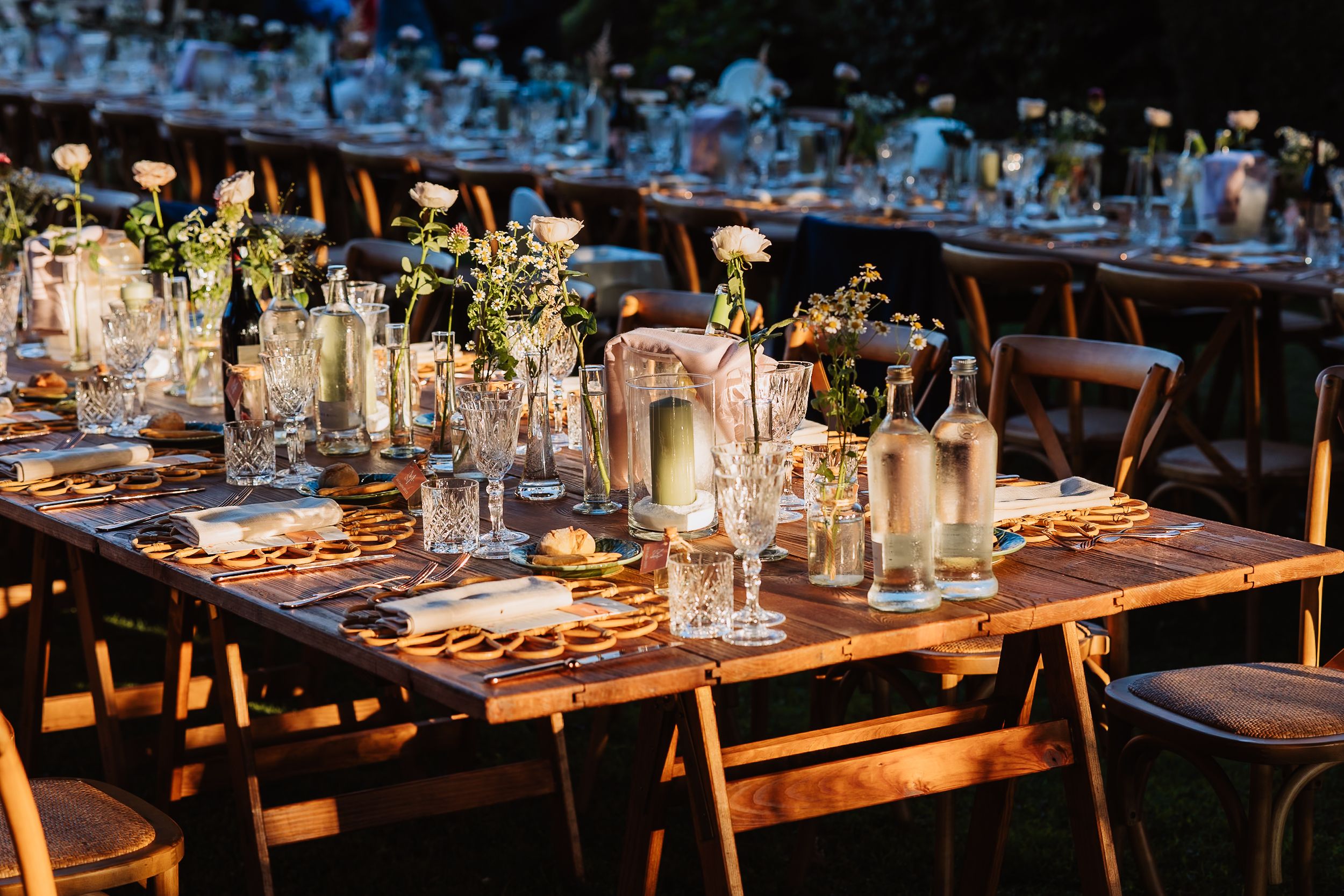 Elegant wedding reception tables set with glowing candles and rustic wooden decor.