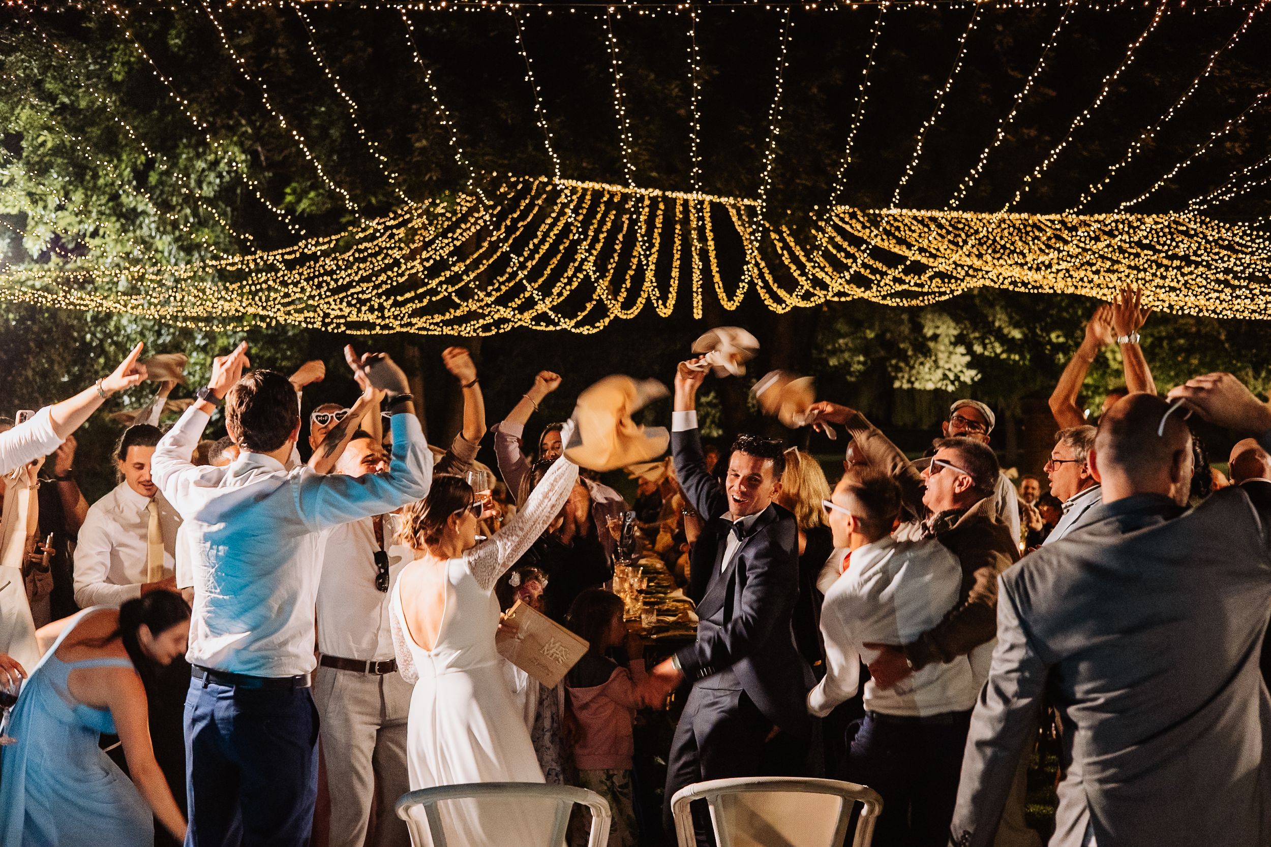 Guests dance beneath a magical canopy of draped string lights creating a romantic outdoor atmosphere.