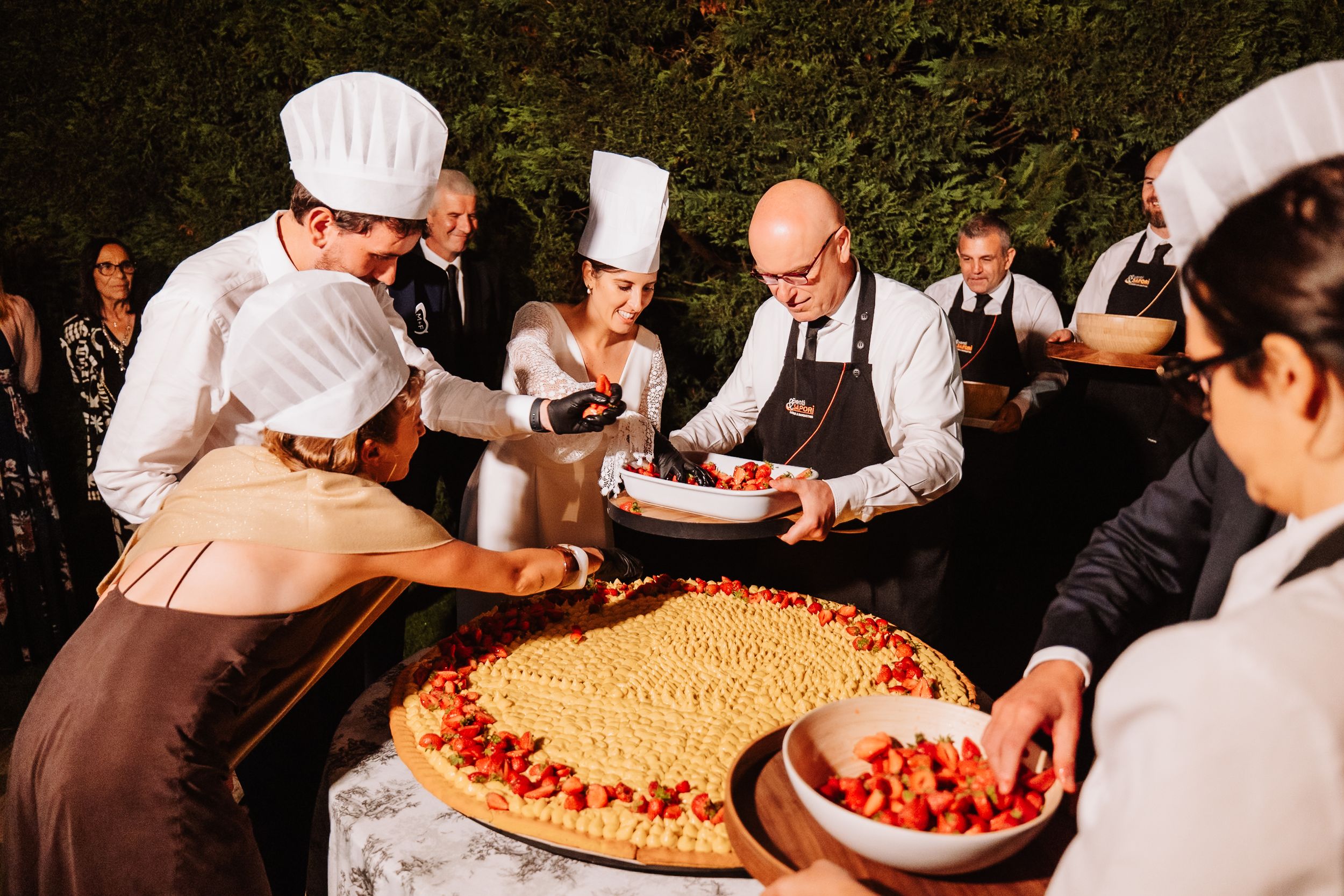Chef prepares fresh wood-fired pizzas at an outdoor wedding reception station.