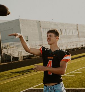 Player in black jersey making animated gestures on football field.