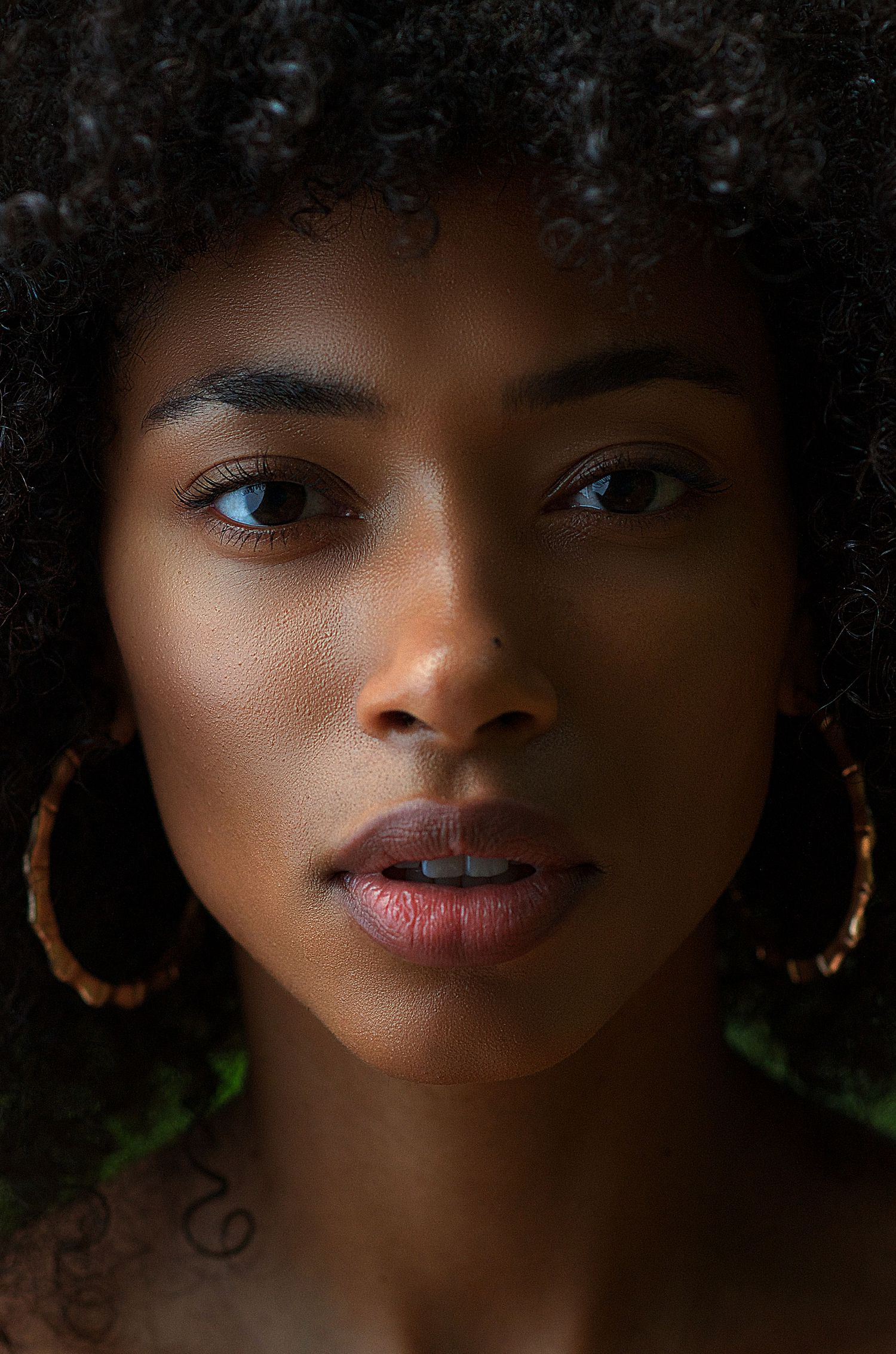 A series of close-up portraits showing natural afro hair and expressive features in dramatic lighting.