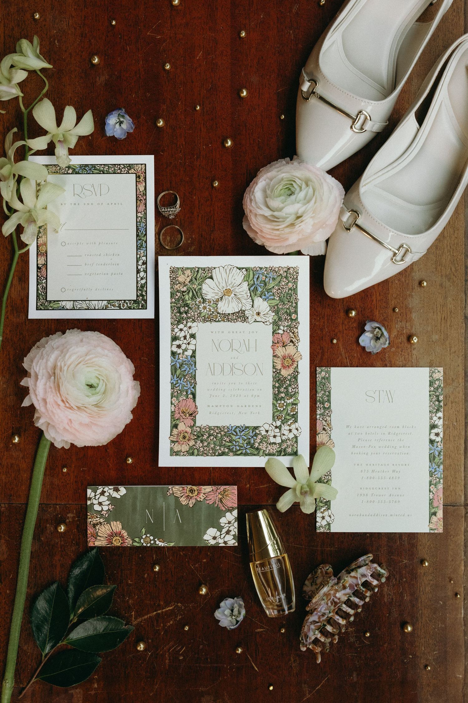 Wedding invitation suite with floral designs, white shoes, and delicate ranunculus flowers arranged on dark wooden surface. Wedding photos