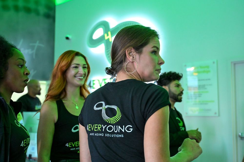 People gathered in an office space illuminated by vibrant green lighting during a business event.