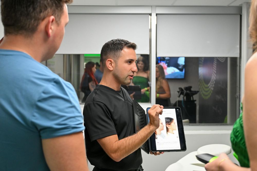 Two people working together in an office setting while looking at documents and computer screens.