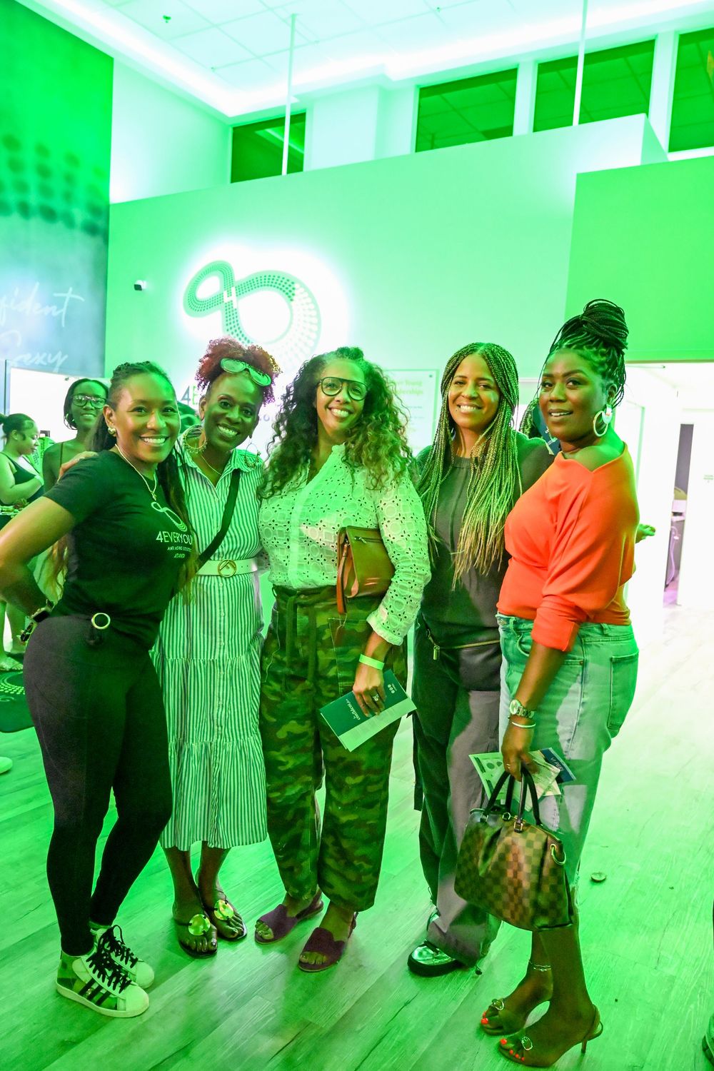 A group of people posing together in a dance studio with green lighting effects on the walls.