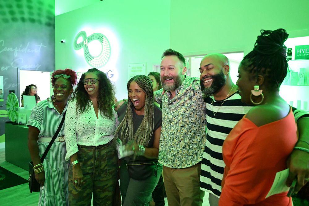A group of people dancing and socializing in a room with bright green lighting and party atmosphere.
