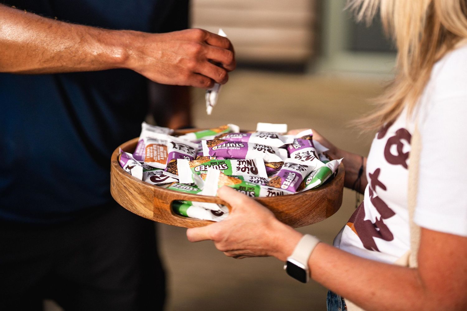 A person's hands holding various snack-sized candy bars and treats in a festive Halloween setting.