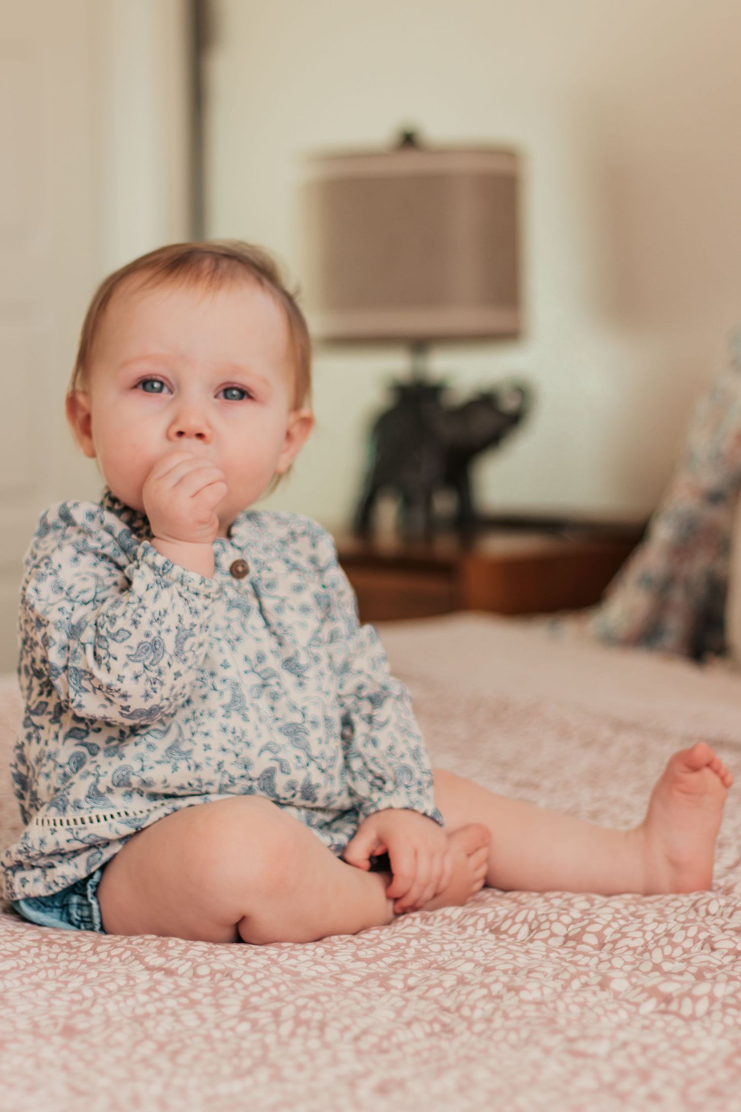 A baby in a green onesie rests on an adult's lap in a series of warm-toned photographs.| Westminster, CO motherhood & family photographer