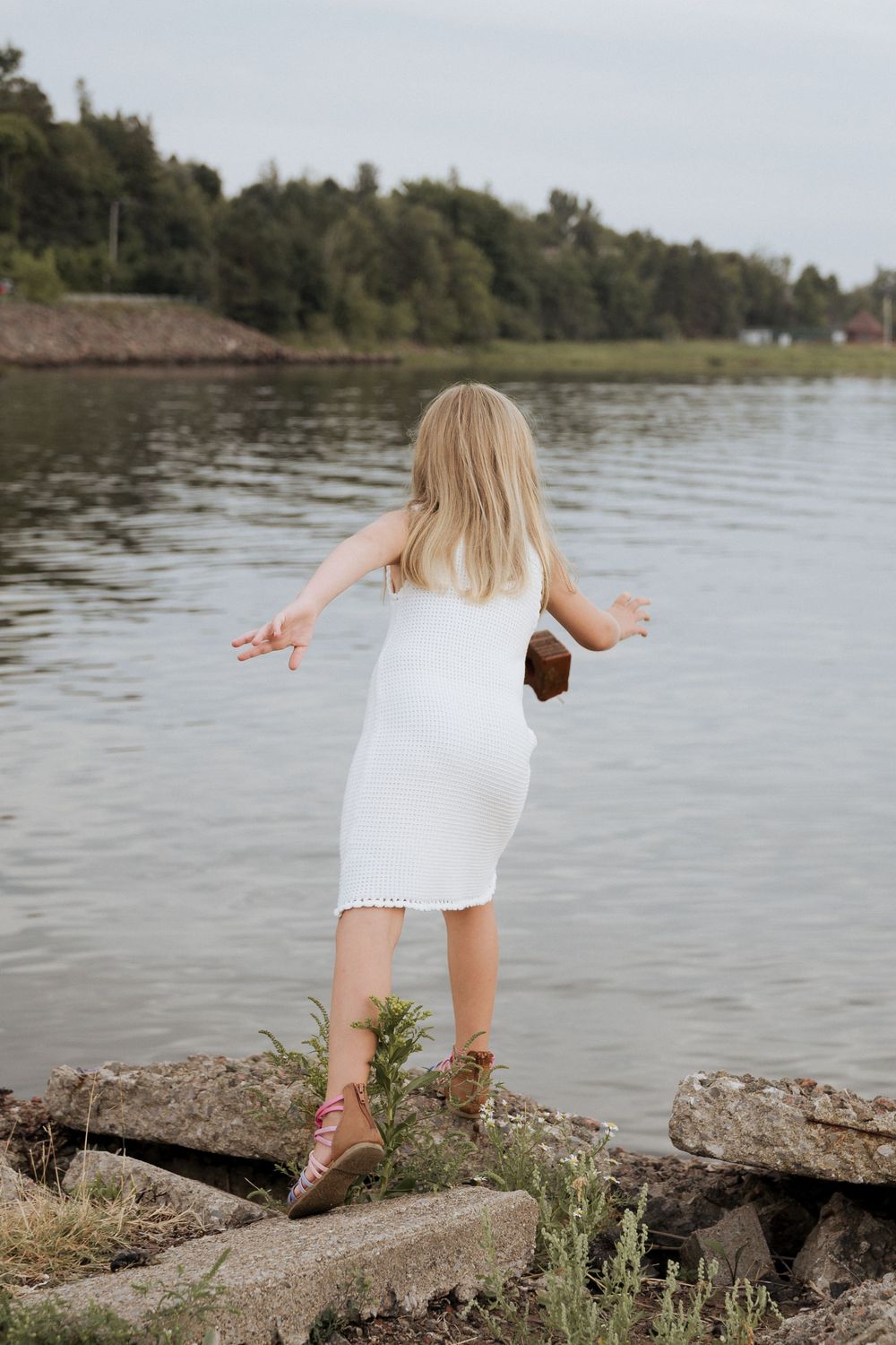 girl throwing rocks in the water, skipping rocks, candid moment photography Shediac photographer, fun family portraits authentic storyteller