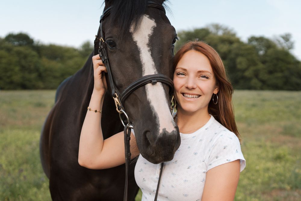 A beautiful black horse and a girl pose together in a sunny green field during an equine photoshoot in Sydney