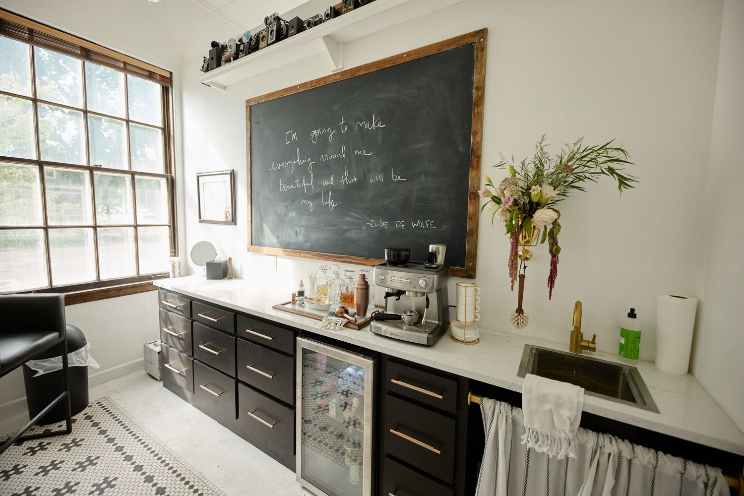 Modern office break room with chalkboard, dark cabinets and minimalist decor.