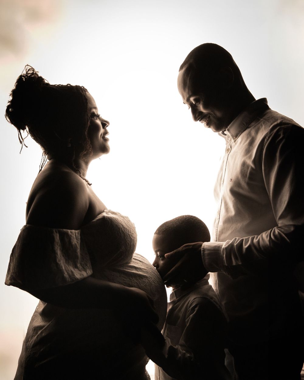Artistic black and white silhouettes showing progression of pregnancy and parenthood in a series of intimate poses.
