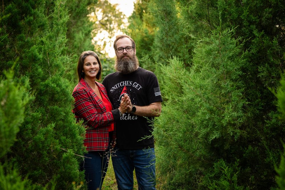 A couple embraces in a lush green garden setting during a romantic outdoor photoshoot at sunset.