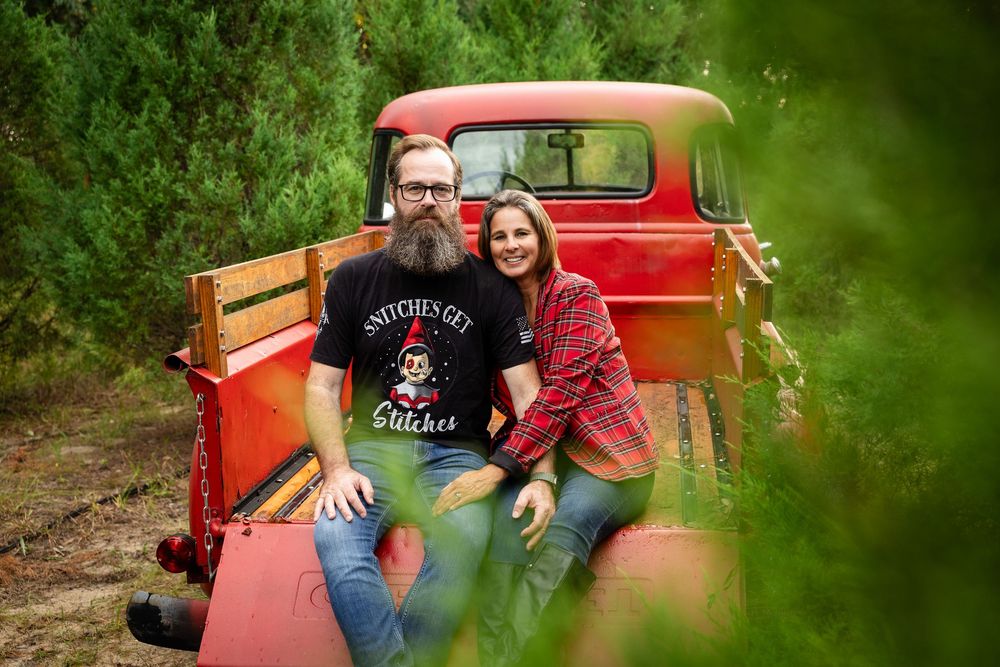 A vintage red truck parked in a lush green forest setting creates a rustic outdoor scene.