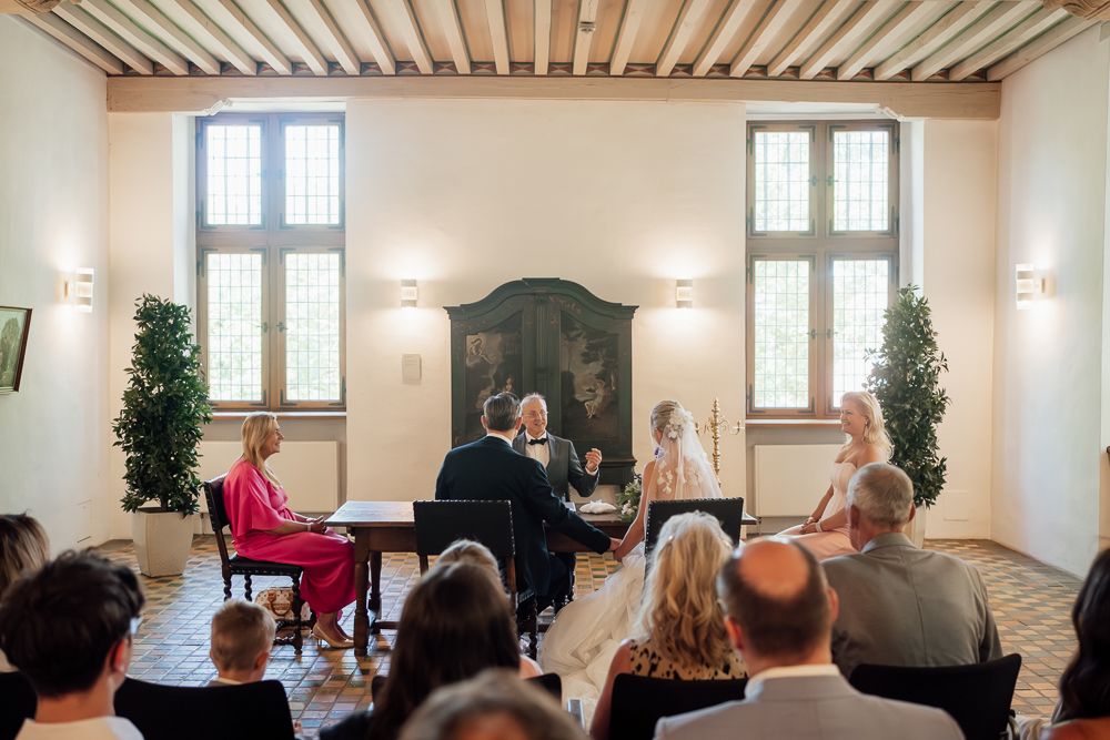 A panoramic view of an elegant white indoor venue with wooden beamed ceiling and wall sconces.