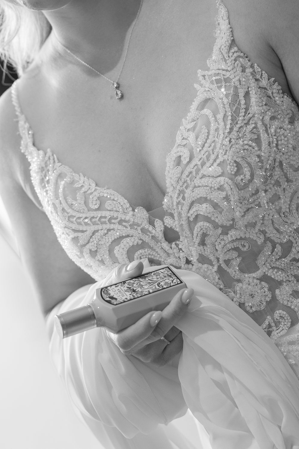 Close-up details of a white lace wedding dress bodice with intricate floral embroidery and delicate beading.