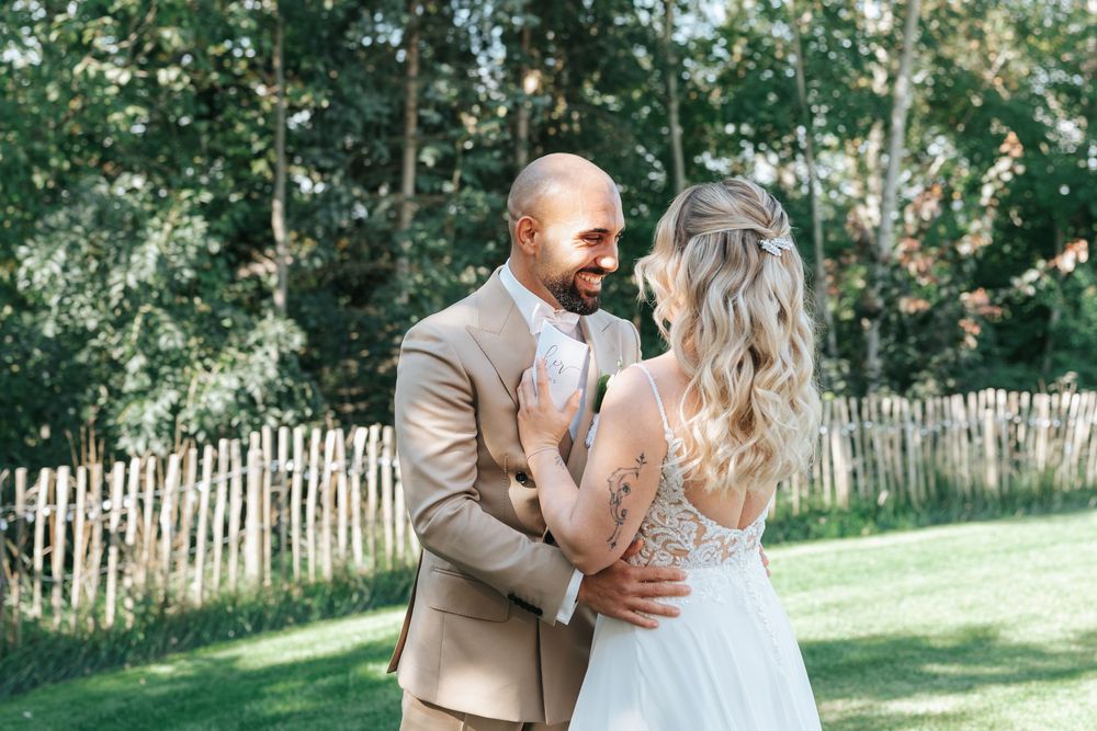 A couple shares a romantic moment together in a sunlit garden setting with a rustic wooden fence in the background.
