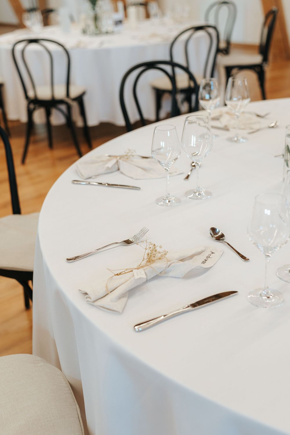 Restaurant table settings with crisp white tablecloths, wine glasses, and elegant silverware in an upscale dining room.