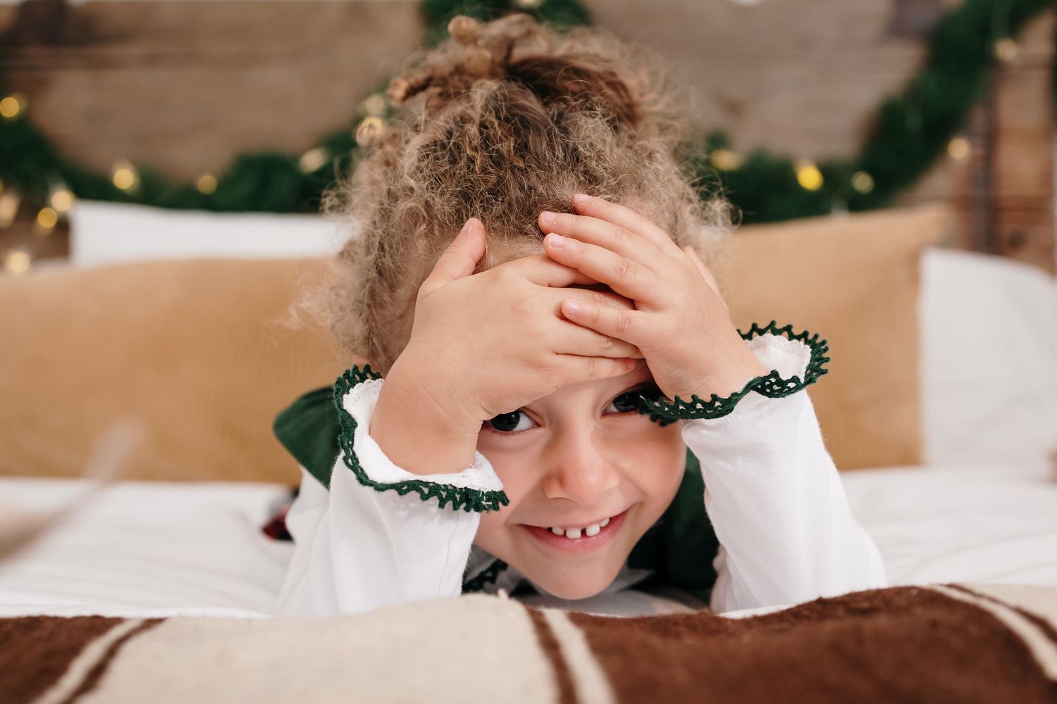 Holiday portrait setup with greenery garland and warm lighting against neutral background.