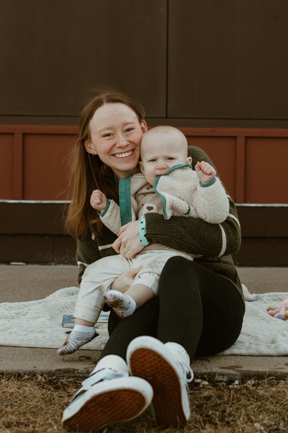 A baby and caregiver peek playfully through a gap under a brown wall in a series of connected photos.
