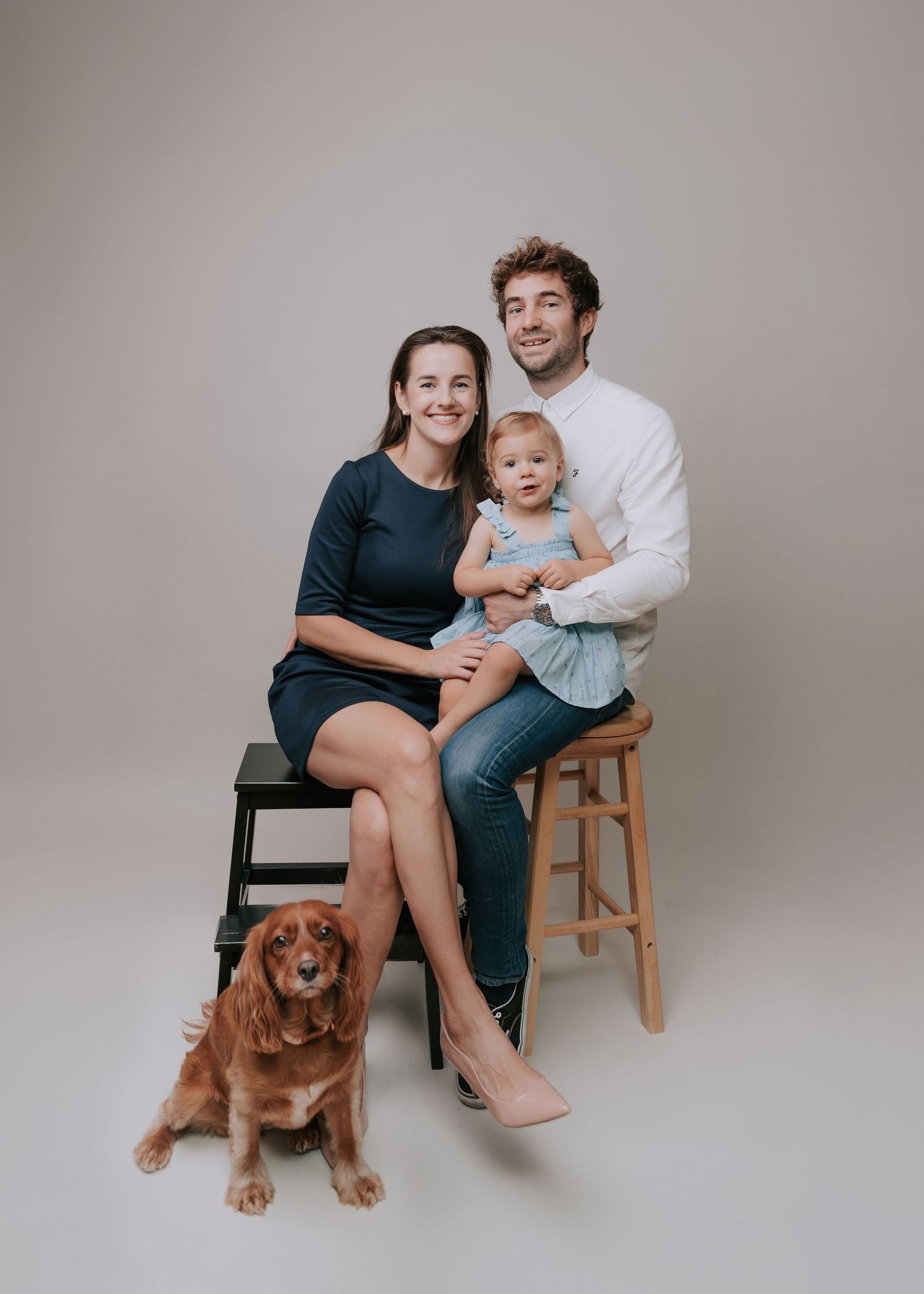 A family and their golden retriever pose together in a series of casual studio portraits against a neutral backdrop.