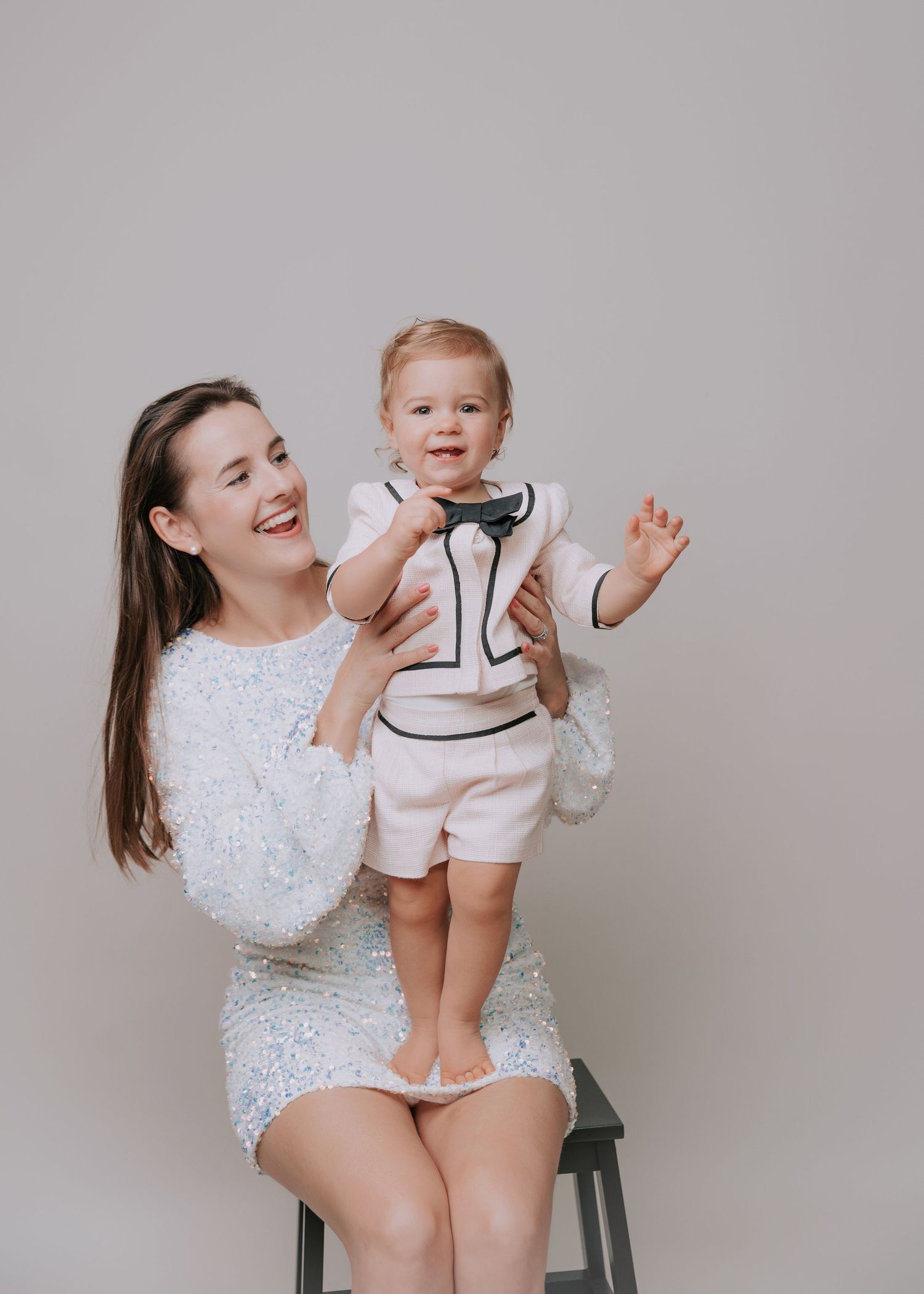 Candid lifestyle portraits showing playful interactions and joyful laughter against a neutral gray backdrop.