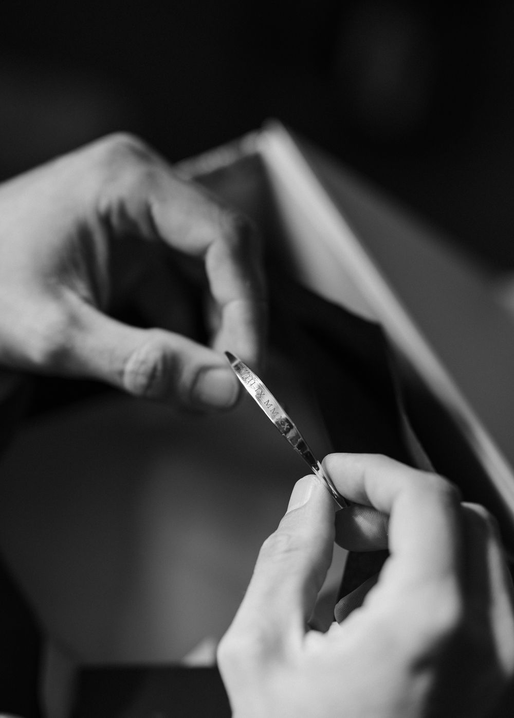 A close-up black and white shot shows hands holding and preparing a syringe for medical use.