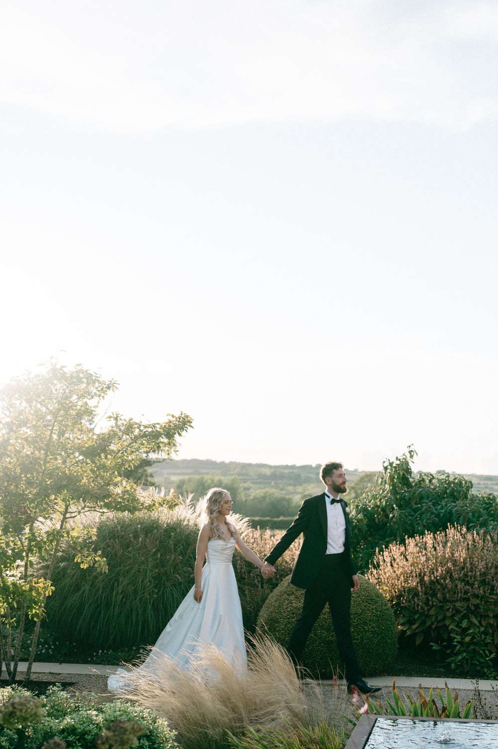 A couple dances together in an outdoor garden setting during sunset with scenic views in the background.