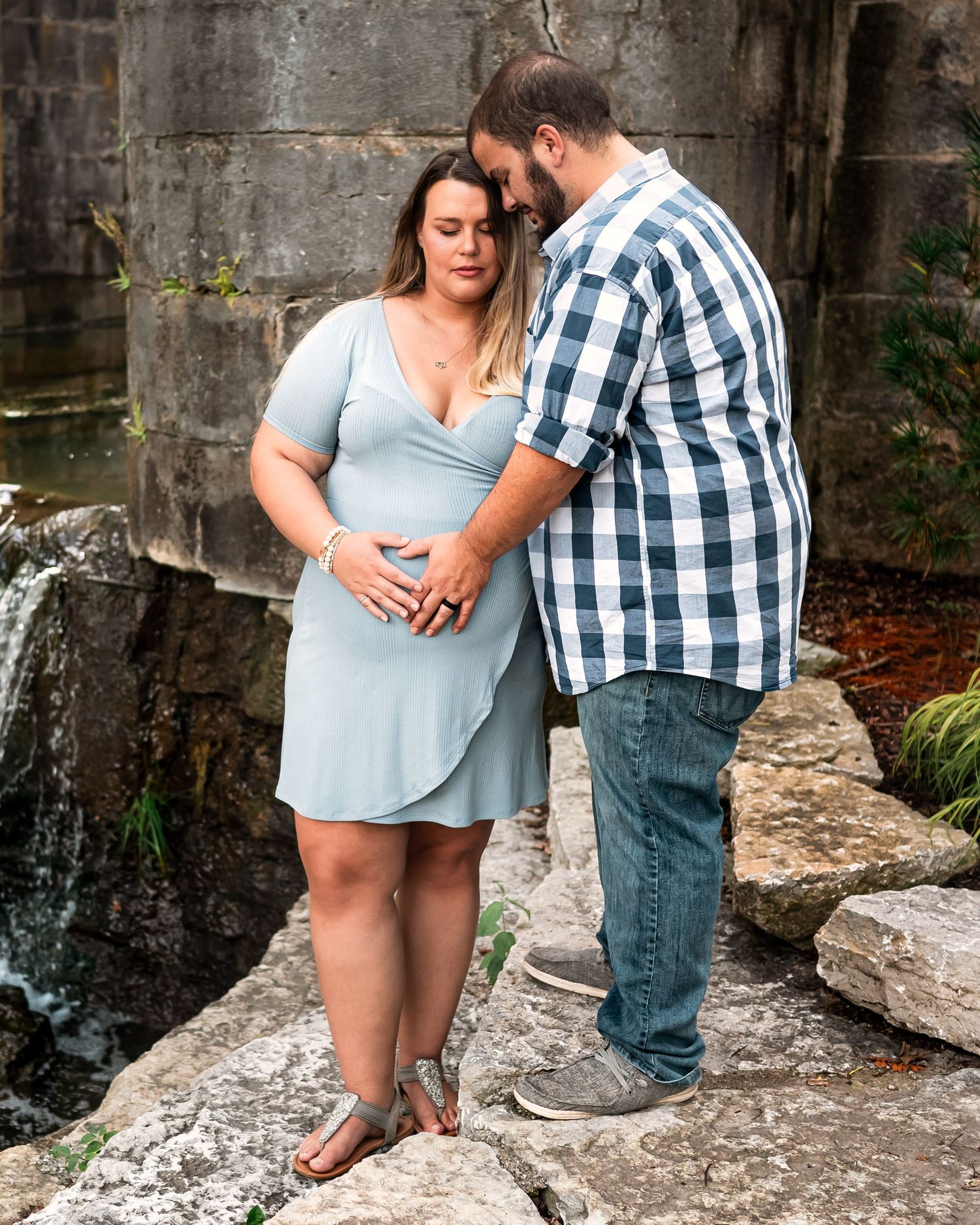 A couple embraces while standing on stone steps in a rustic outdoor setting during a photo session.