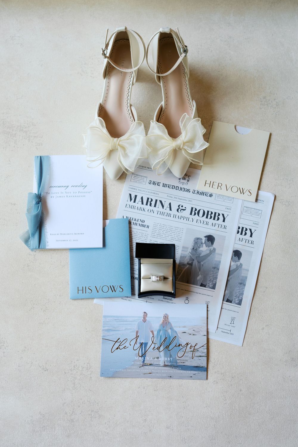 Wedding details flat lay featuring invitations, vows, rings, and elegant shoes arranged on a neutral background.