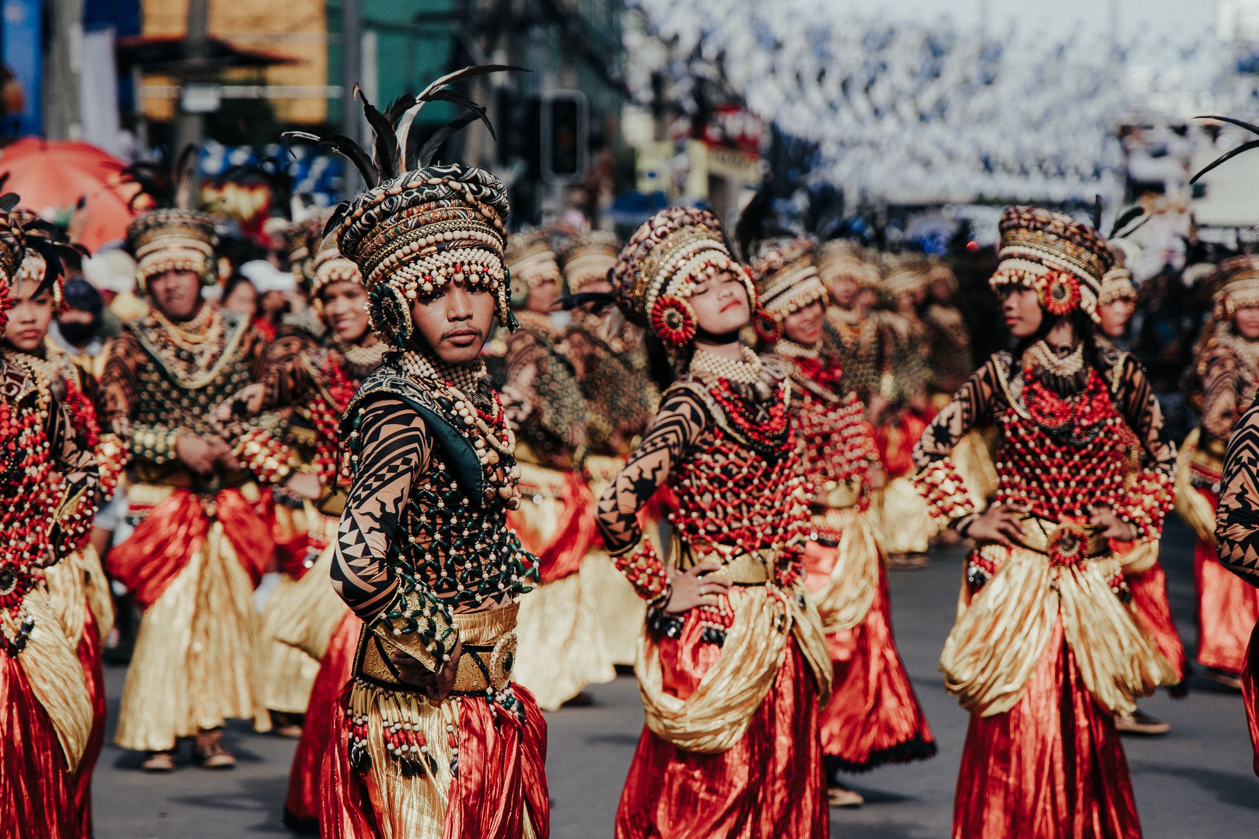 Street parade performers in matching red and gold traditional attire dancing in formation.