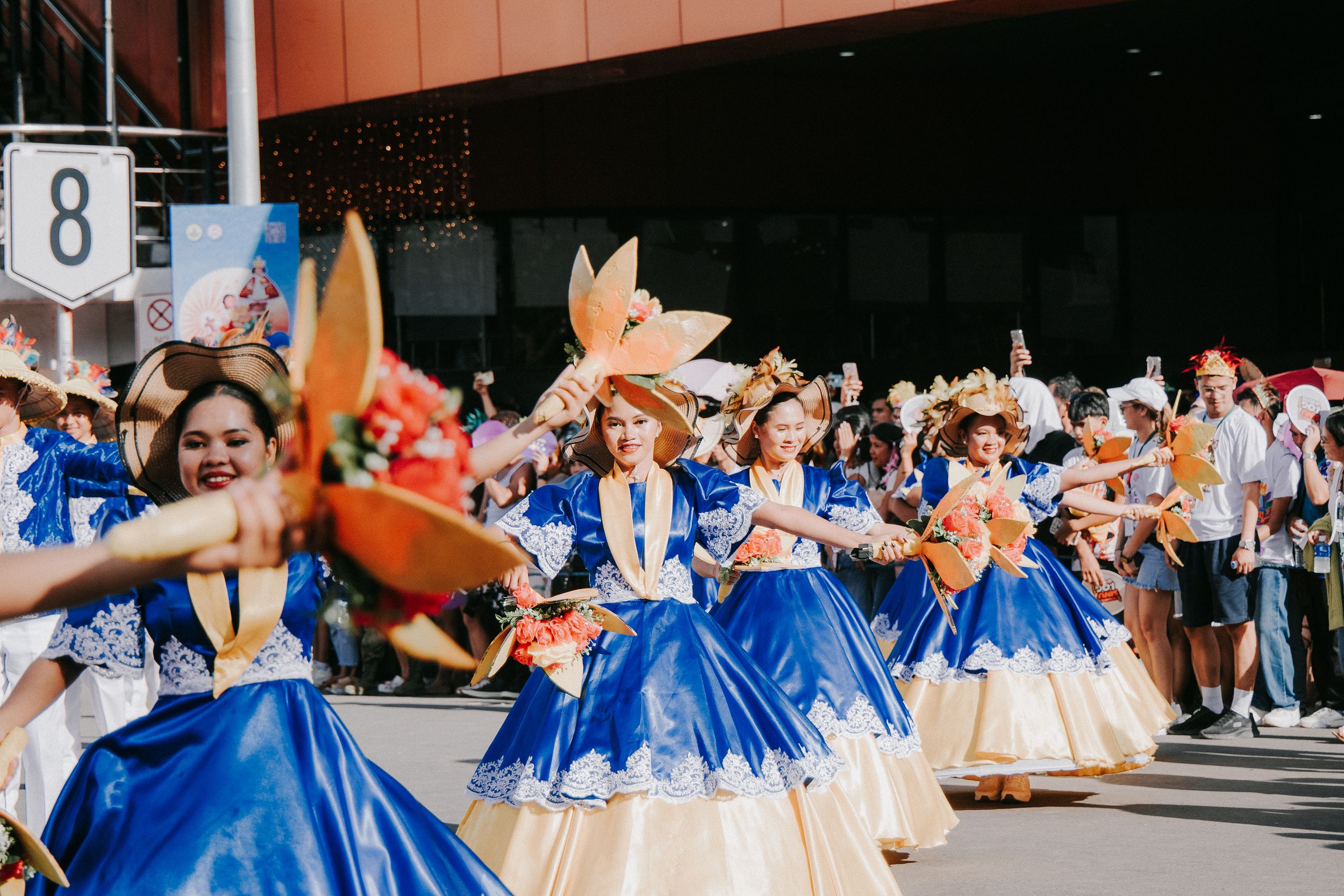 Street parade featuring performers in blue and white costumes dancing in formation.