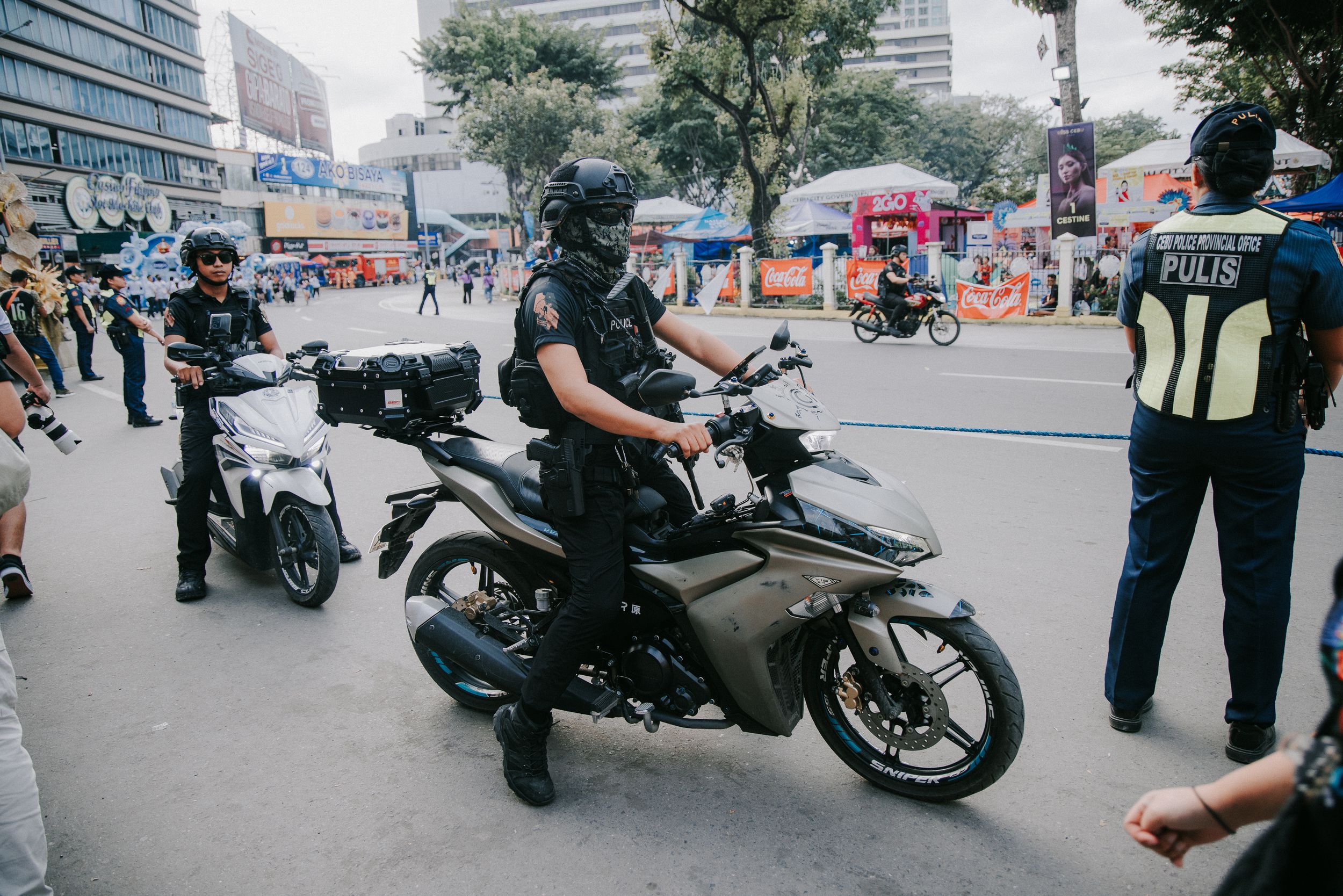 Police officers and motorcycles lined up on a city street during an event.