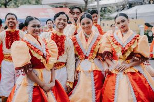 Performers in vibrant red and orange traditional costumes celebrating at a cultural festival.