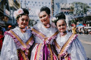 Performers wearing ornate purple and white traditional costumes at cultural festival.