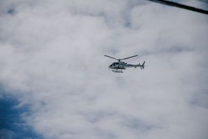 Helicopter flying against cloudy sky during daytime event.