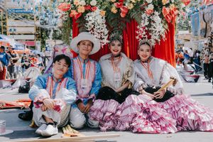 Festive street scene with pink floral decorations and traditional costumes during a cultural celebration.