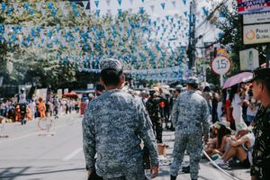 Street festival with blue bunting decorations and military personnel marching in formation.