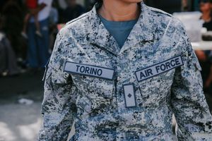 Military service members in digital camouflage uniforms standing at attention during an event.