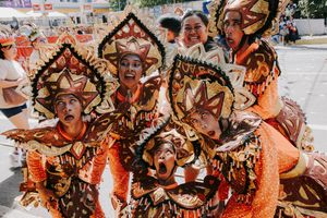 Performers wearing elaborate orange and gold masks during a cultural festival parade.