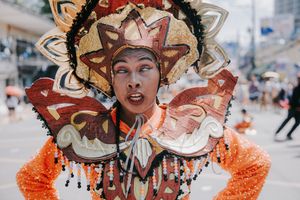 Detailed view of ornate festival masks with intricate designs in orange and gold colors.